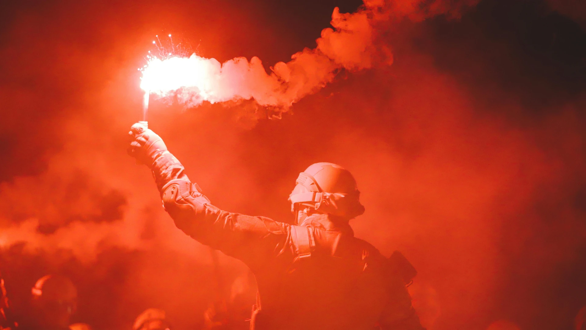 Marsa Alam, Egypt - Soldier signals with a red flare, surrounded by dense smoke and darkness, creating a dramatic scene.