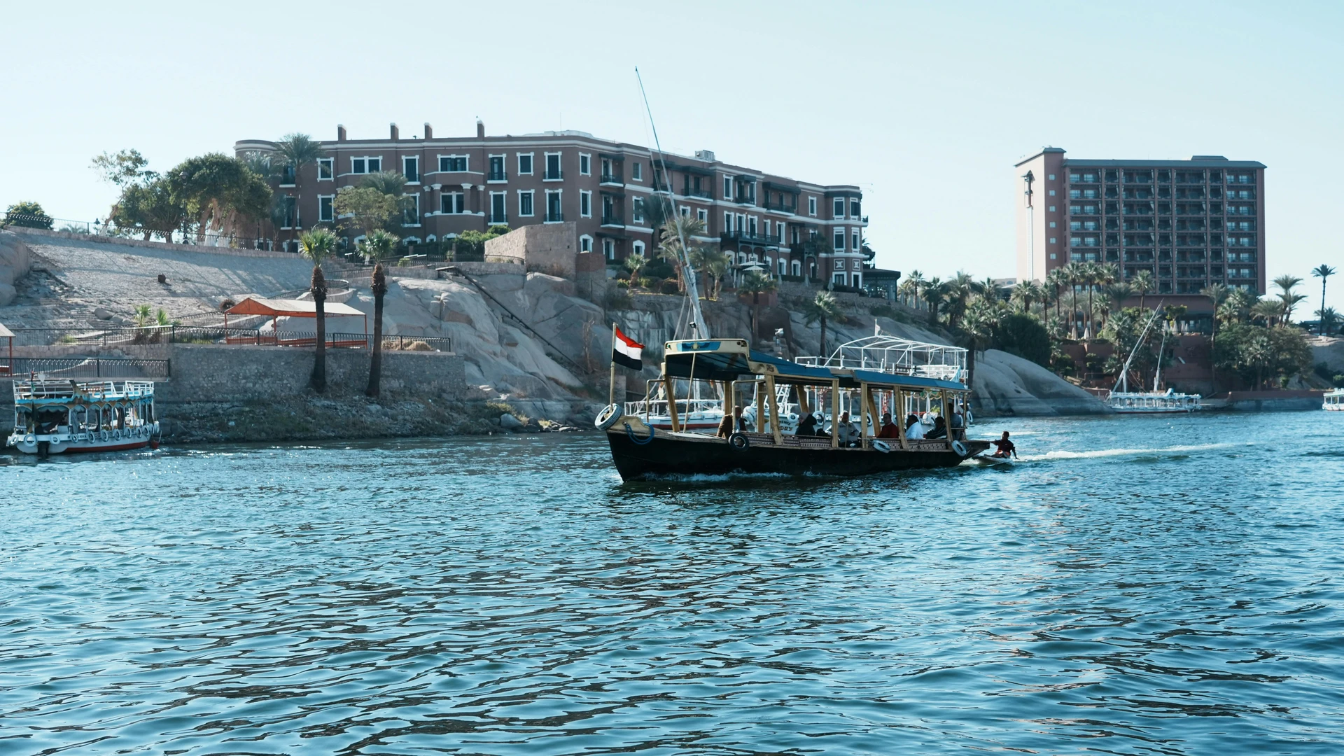 Aswan, Egypt - Scenic view of tour boats navigating the nile river with architectural backdrop in aswan, egypt.