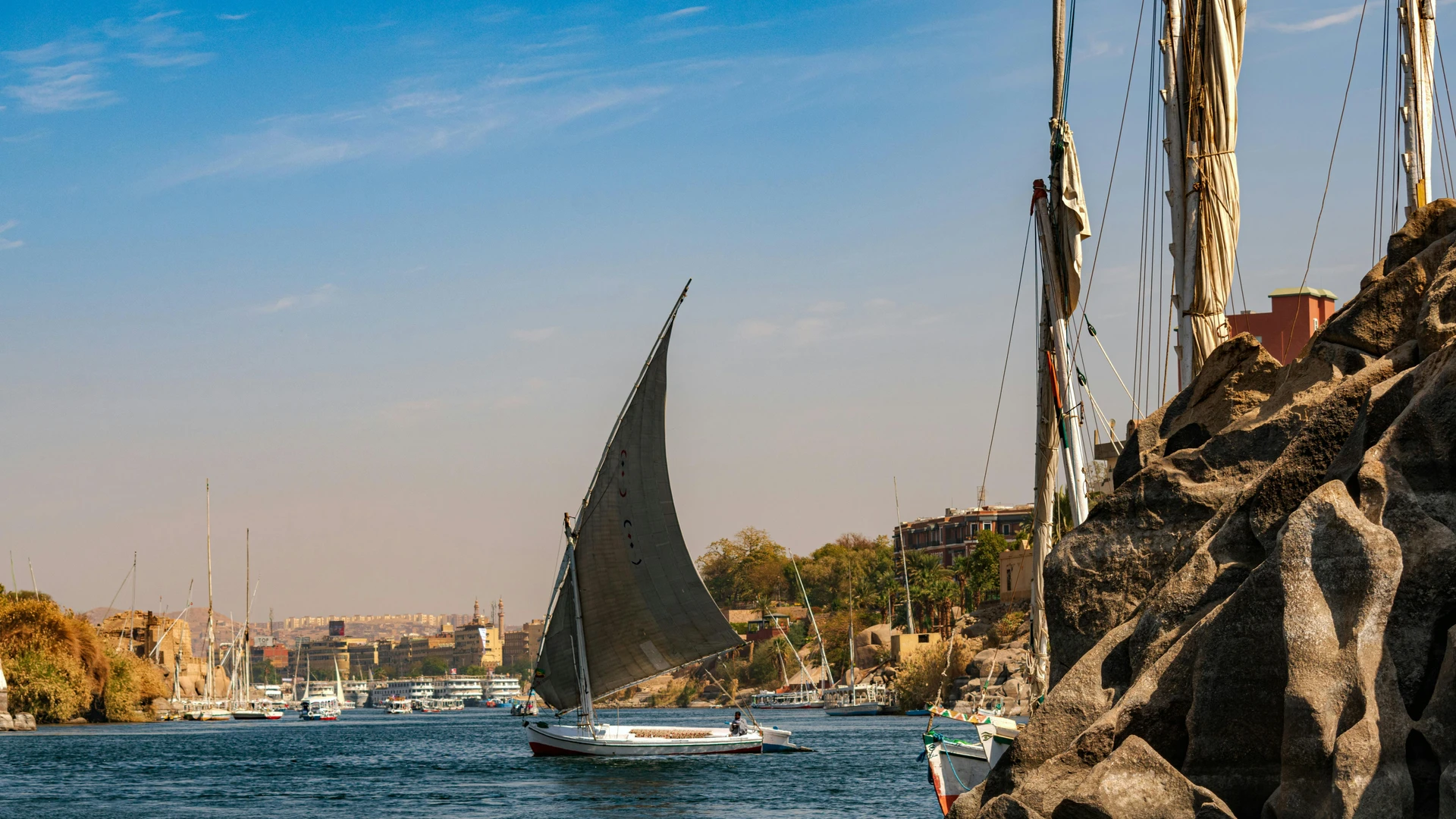 Aswan, Egypt - Traditional sailboat glides on the scenic nile river near aswan, egypt, showcasing a tranquil landscape.