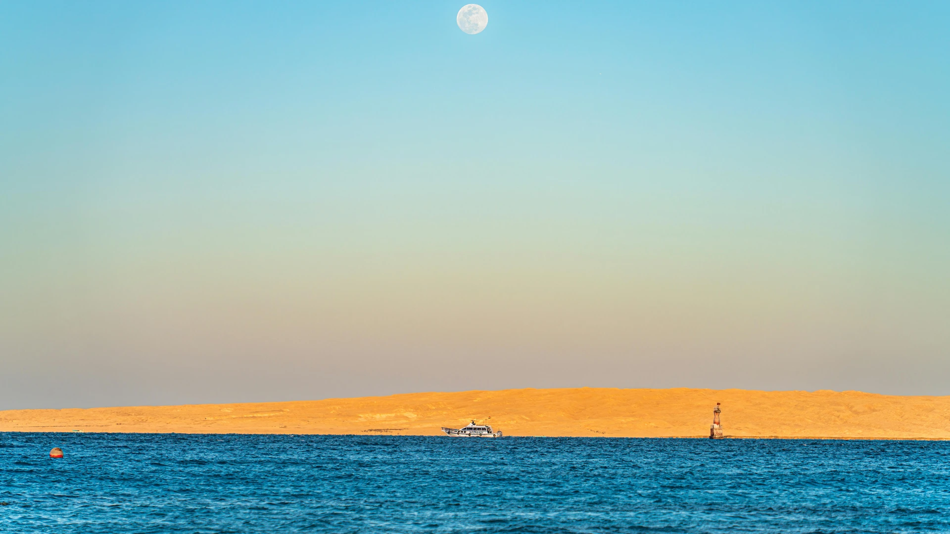 Hurghada, Egypt - Serene view of the red sea in hurghada, egypt, with a full moon rising above golden sand dunes.