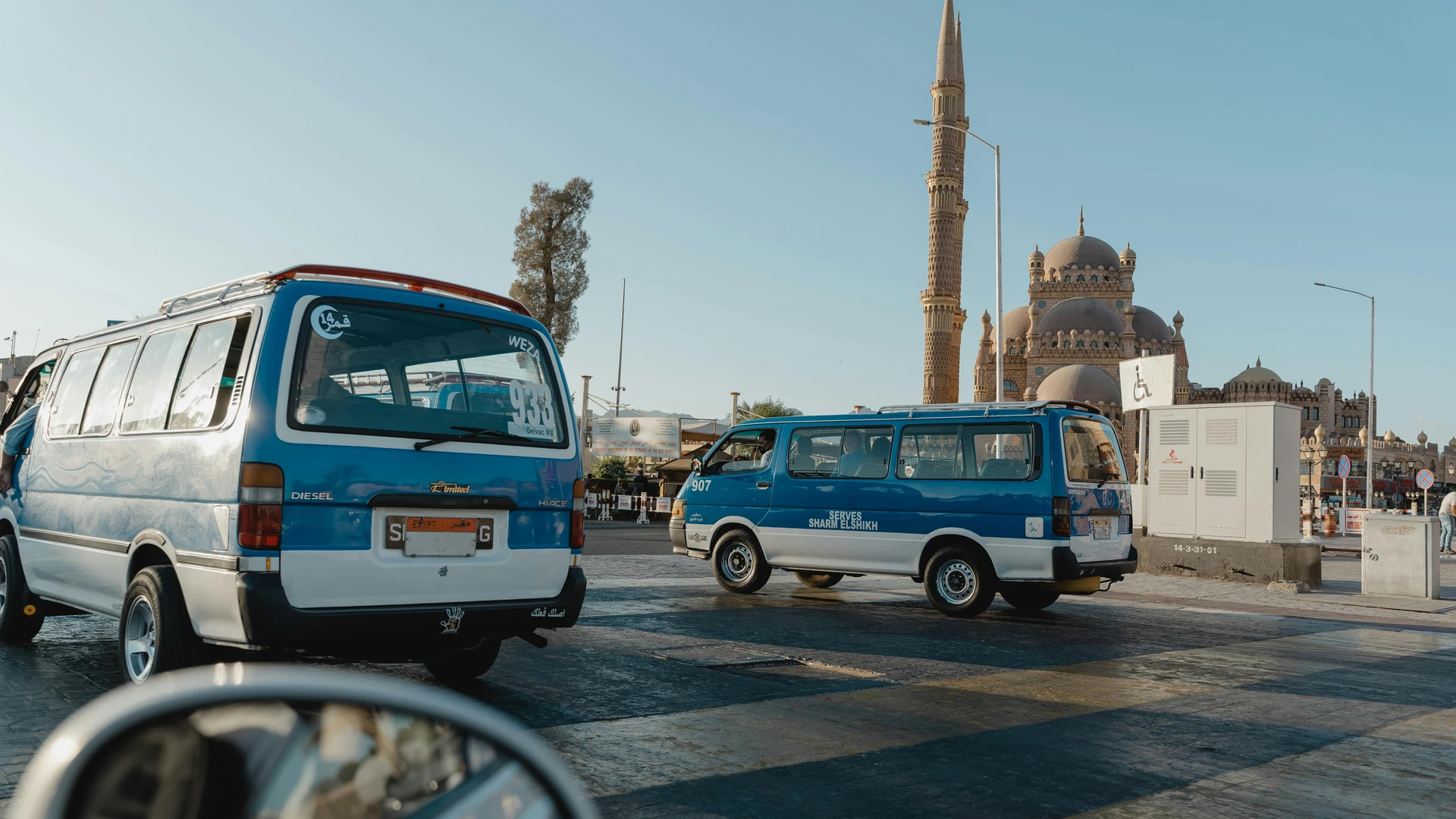 Sharm El Sheikh, Egypt - View of a city street featuring a mosque and parked minivans under clear skies.